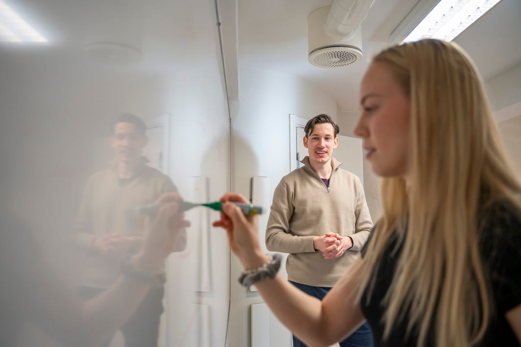 Privatist skriver på en tavle med lærer i bakgrunnen