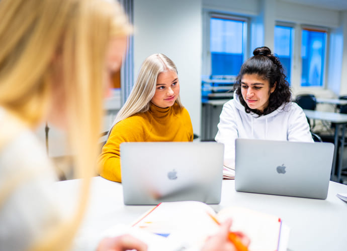 Tre privatister som sitter sammen og jobber på Mac. Foto.