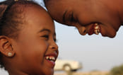 Et barn og en ungdom i Somalia, med hodene mot hverandre som smiler og ler. Foto.