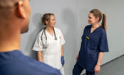 Tre medisinstudenter som snakker sammen i gangen på sykehus. Foto.