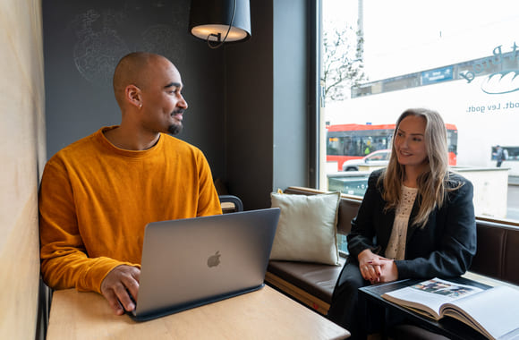 Privatist som arbeider med fag på kafe, og prater med venninne. Foto.