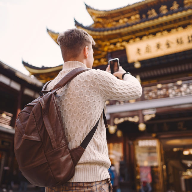 Turist i kina tar bilde av gamle skulpturer og bygninger