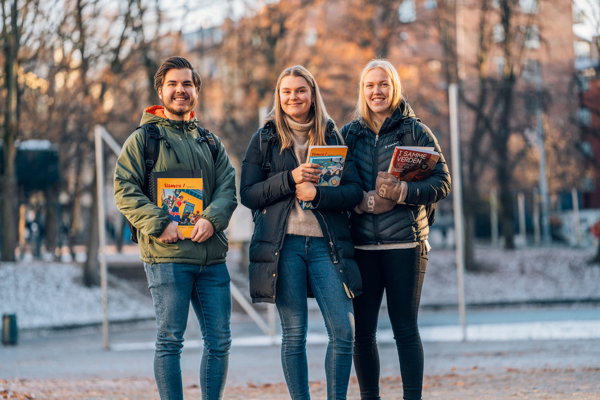 Tre privatister står utendørs med bøker og Mac fra Akademiet Privatistskole