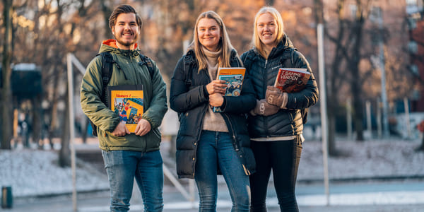 Tre privatister står utendørs med bøker og Mac fra Akademiet Privatistskole