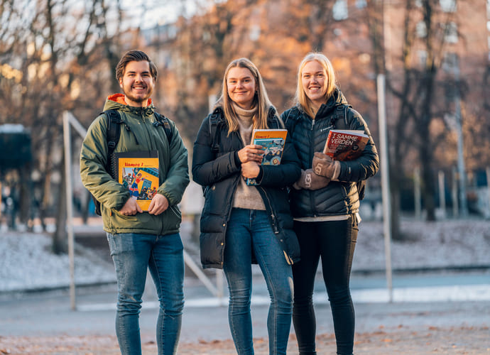 Tre privatister står utendørs med bøker og Mac fra Akademiet Privatistskole