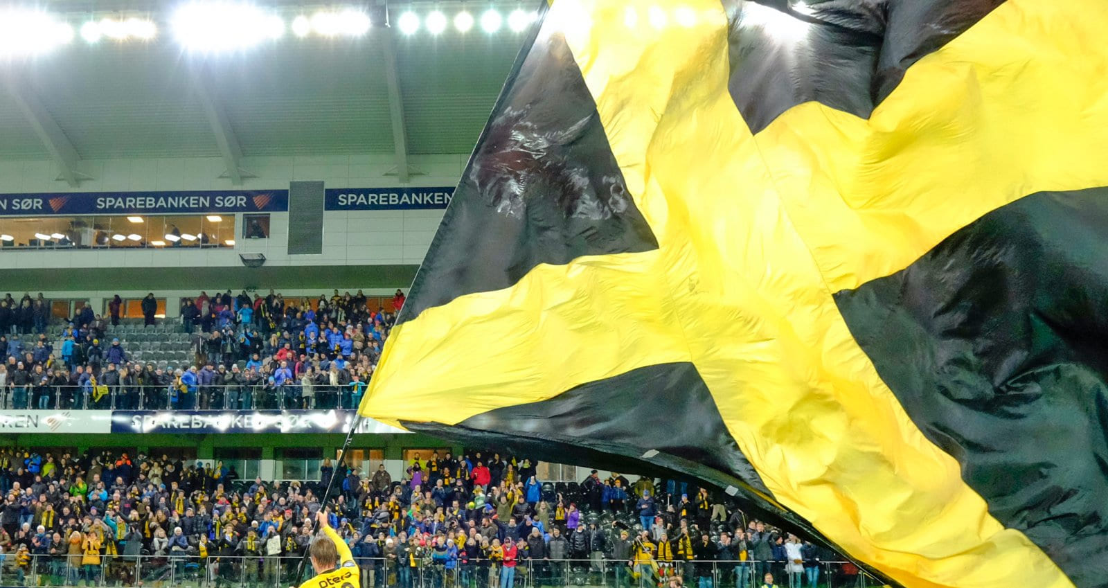 Start-flagget vaier på IK Start sin stadion med fullsatt tribune