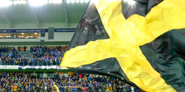 Start-flagget vaier på IK Start sin stadion med fullsatt tribune