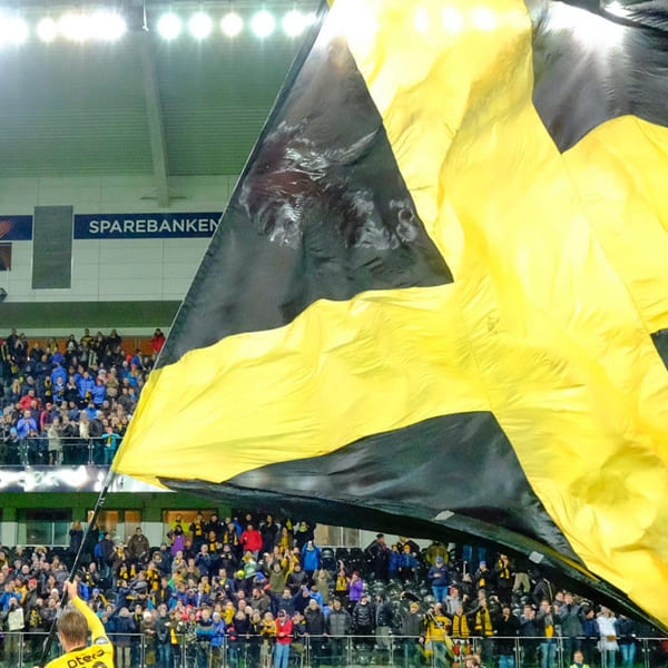 Start-flagget vaier på IK Start sin stadion med fullsatt tribune
