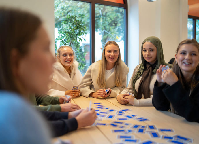 Elever spiller kort sammen rundt et bord på Akademiet VGS Bergen