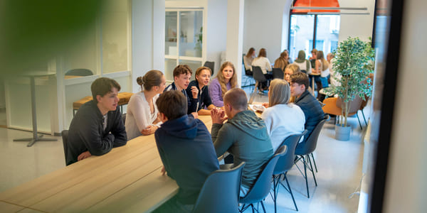 Elever prater sammen rundt et bord på Akademiet VGS Bergen