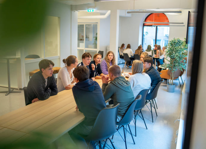 Elever prater sammen rundt et bord på Akademiet VGS Bergen