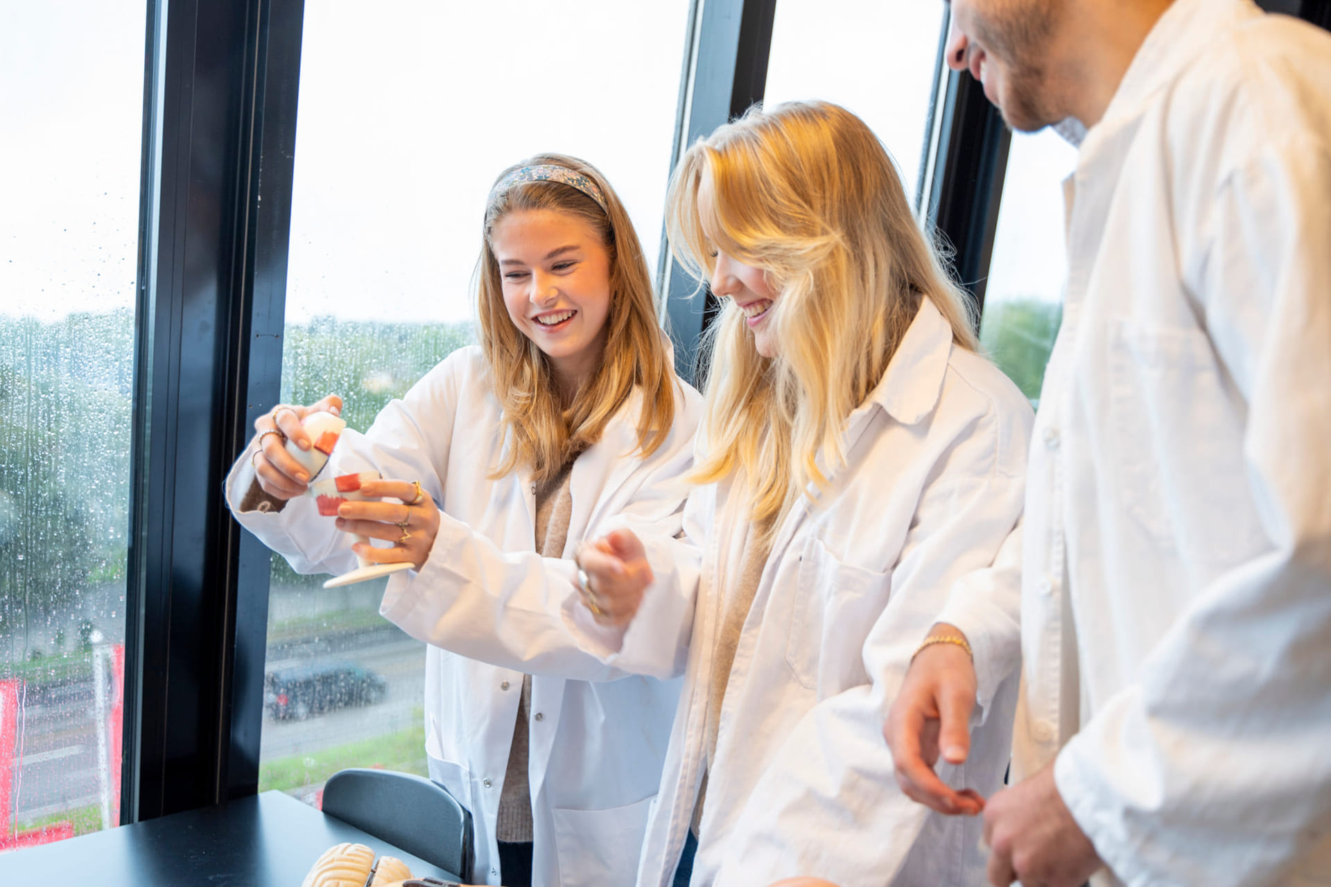 Tre elever i realfagsfrakker i laben på Akademiet VGS Heltberg Ullevaal.