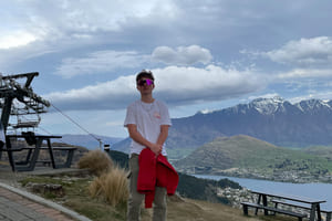 Oliver Knarud står på en topp med utsikt utover New Zealand.
