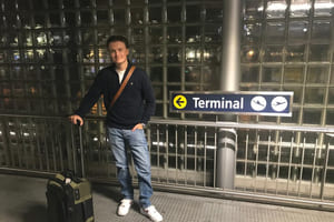 Carl står på flyplassen i Norge med kofferten, klar for å reise.