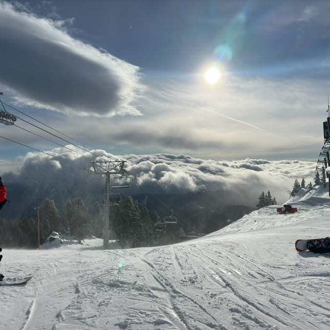 Bilde av en alpinbakke i blå himmel og sol.