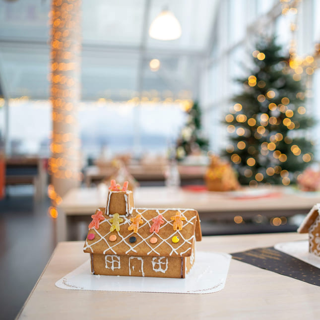 Pyntede pepperkakehus med juletre i bakgrunnen