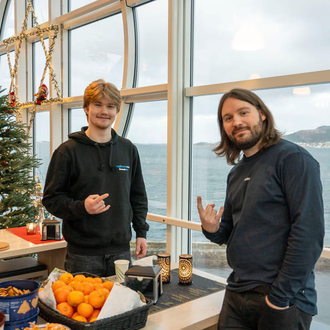 Lærer og tidligere elev smiler til kamera på Akademiet VGS Ålesund