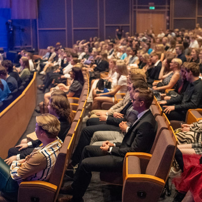 Elever og foresatte sitter i auditoriet og ser på Akademiet Awards.