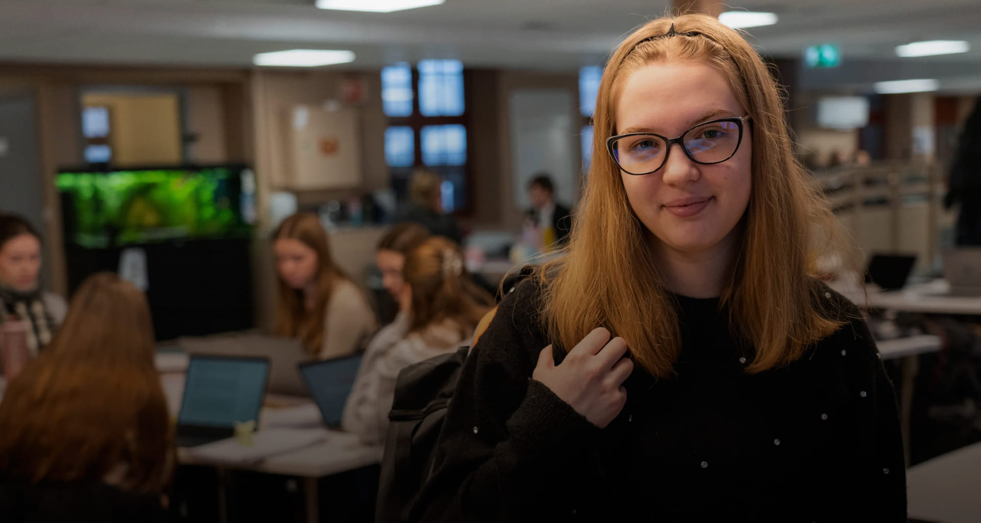 Rahela smiler mot kamera mens klassekameratene sitter i bakgrunn