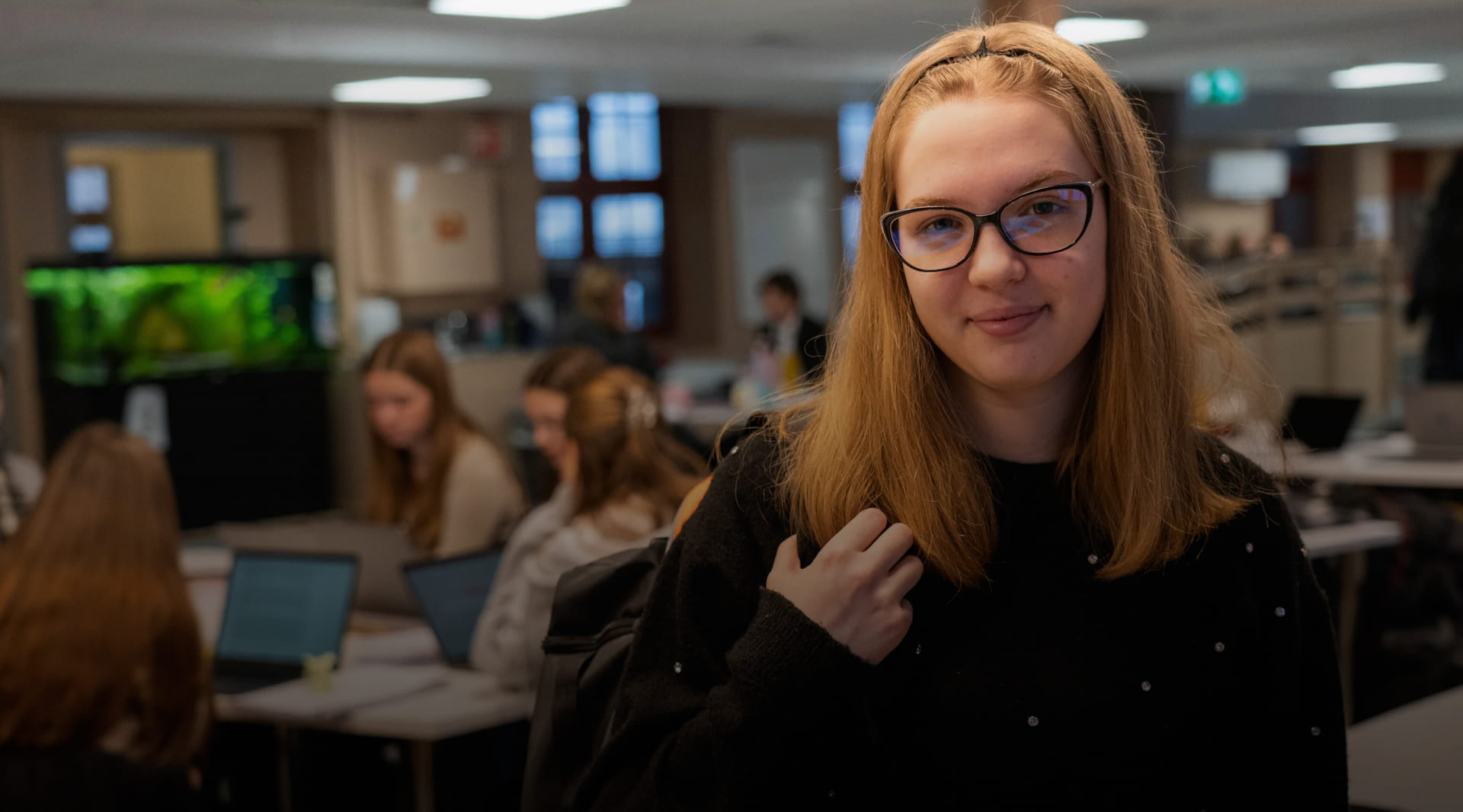 Rahela smiler mot kamera mens klassekameratene sitter i bakgrunn
