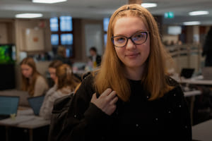 Rahela smiler mot kamera mens klassekameratene sitter i bakgrunn