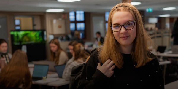 Rahela smiler mot kamera mens klassekameratene sitter i bakgrunn