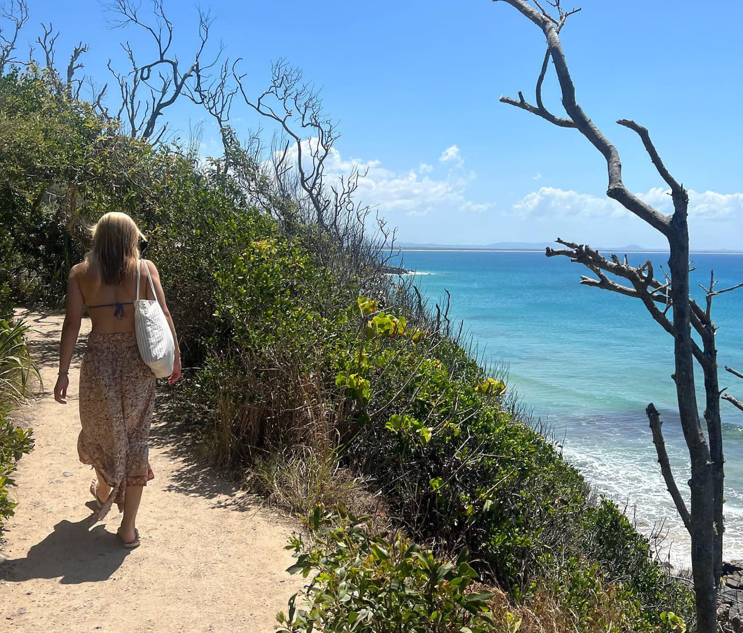 Jente går langs en ås ved en strand i australia