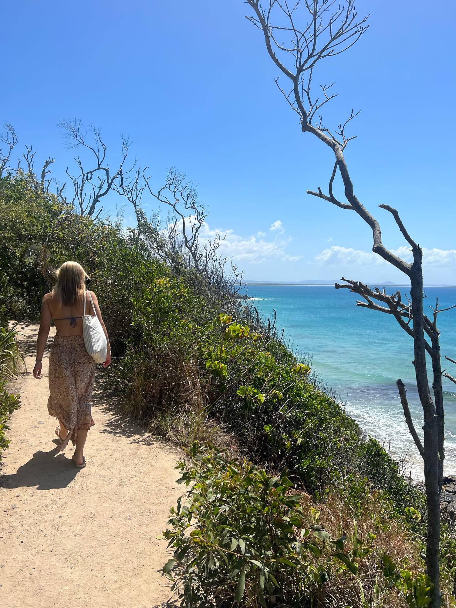 Jente går langs en ås ved en strand i australia