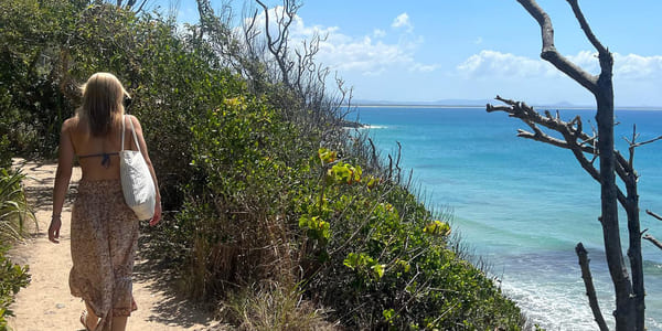 Jente går langs en ås ved en strand i australia