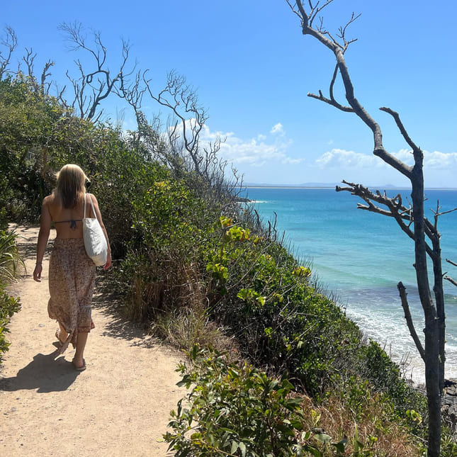 Jente går langs en ås ved en strand i australia