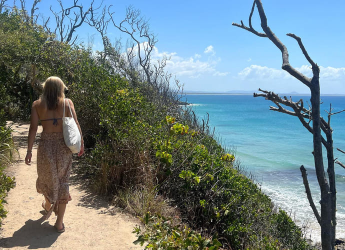 Jente går langs en ås ved en strand i australia
