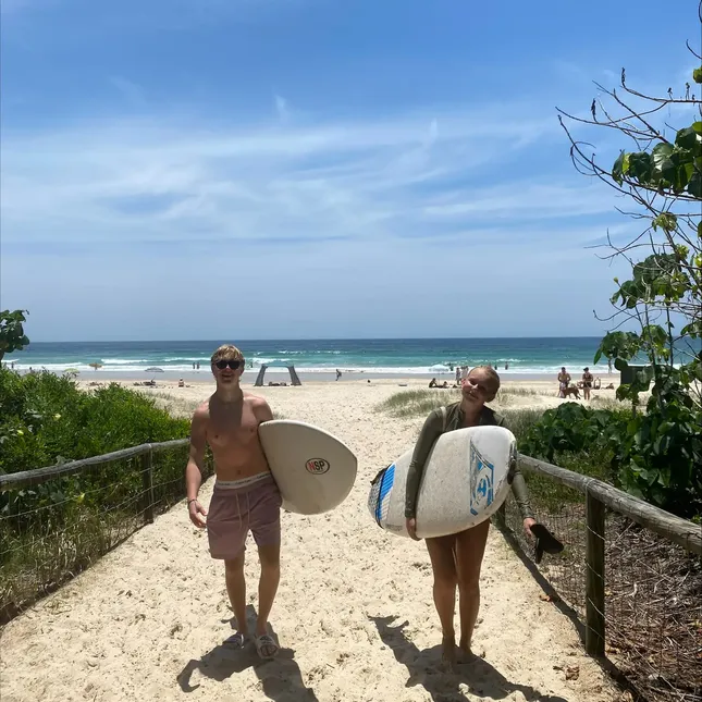 to personer går fra stranda med surfebrett under armen