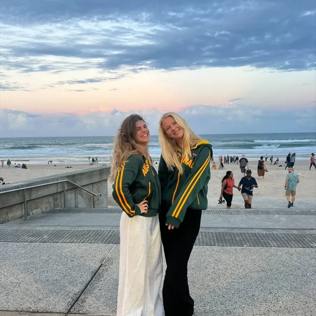 Emma og en venninne poserer på promenaden ved stranda