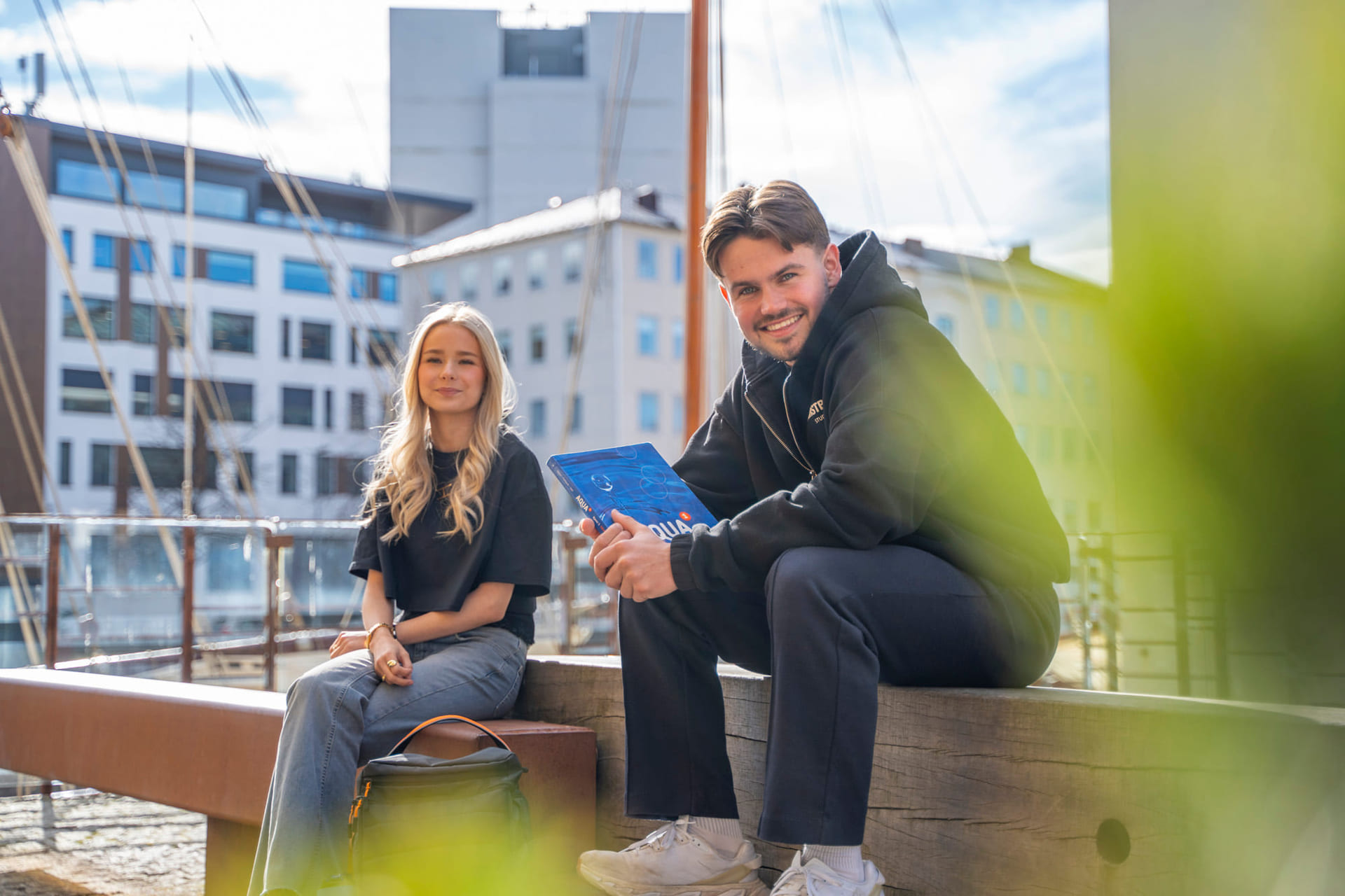 To privatister sitter på en benk med sol i bakgrunn