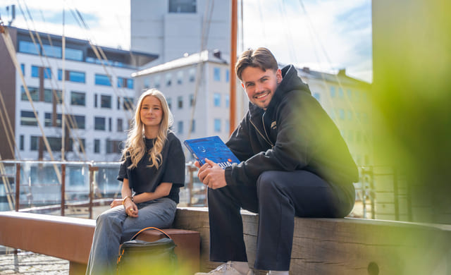 To privatister sitter på en benk med sol i bakgrunn