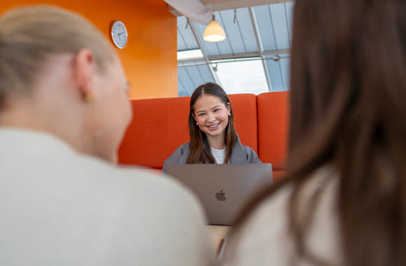 Tre privatister sitter sammen rundt et bord og leser med bøker og macbook.