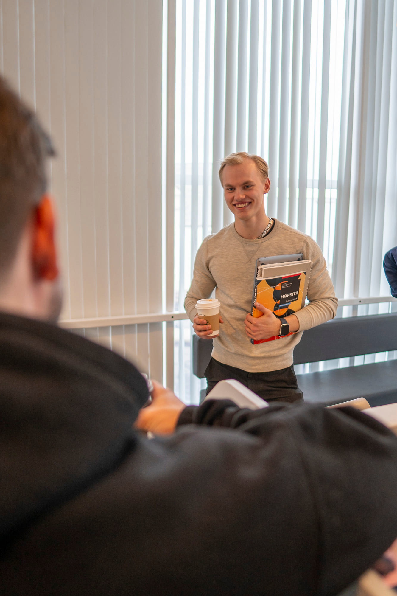 Privatist står med kaffe og mattebok på Akademiet