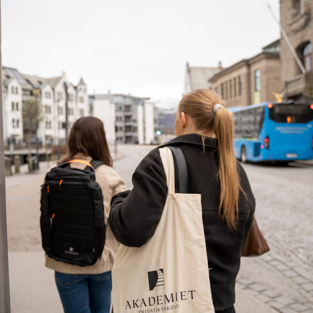 To jenter går bortover et fortau i en by