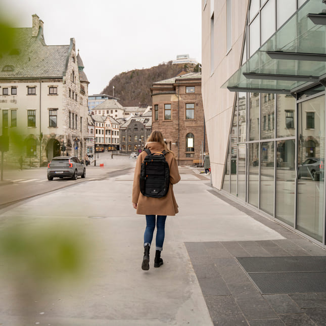 Privatist går i sentrum av en by med Akademiet-sekken på ryggen