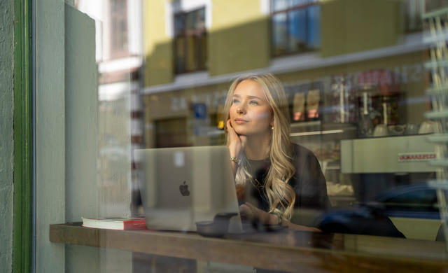 Elev sitter på en kafé med macbook for å studere