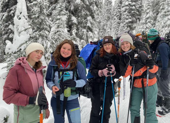 Johanna med flere venner smiler på tur i skogen i snødekte landskap.
