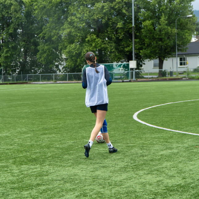 Jente på fotballtrening løper etter ballen