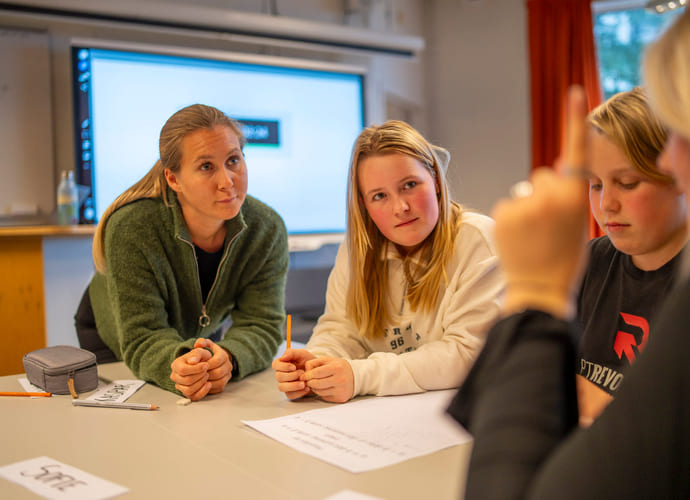Lærer og elever i diskusjon i klasserommet.