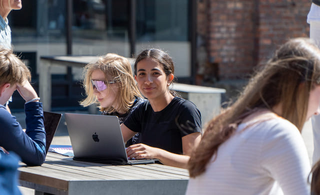 Elever sitter utendørs og jobber med skole