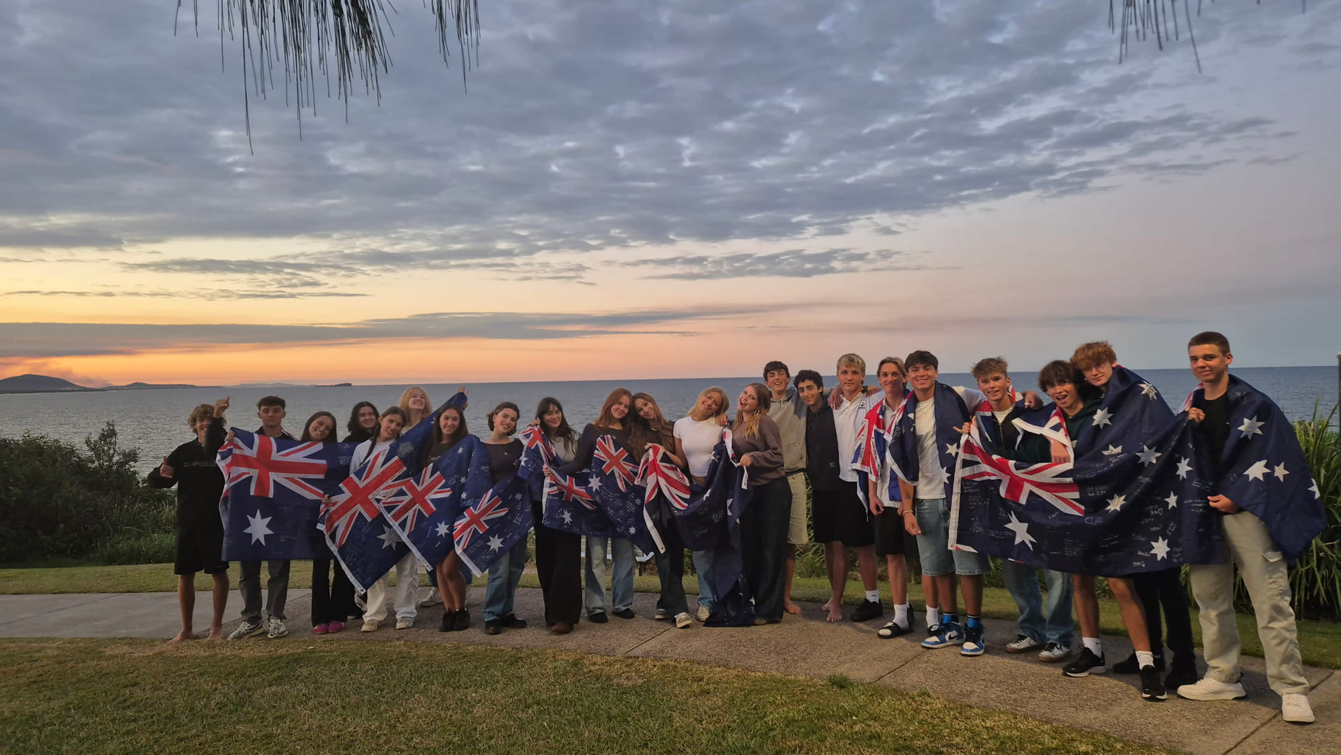 En stor gjeng med internasjonale elever som går på Maroochydore State High School poserer med det australske flagget rundt seg