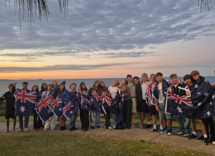 En stor gjeng med internasjonale elever som går på Maroochydore State High School poserer med det australske flagget rundt seg